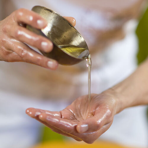 Massageöl in Schale und Händen