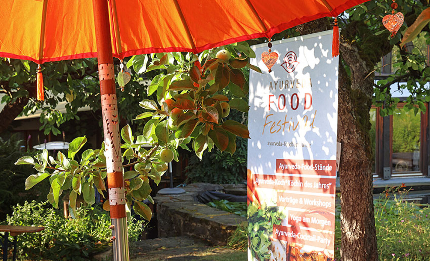 Stand mit ayurvedischen Speisen unter rotem Sonnenschirm beim Food Festival des Rosenberg Ayurveda Zentrums