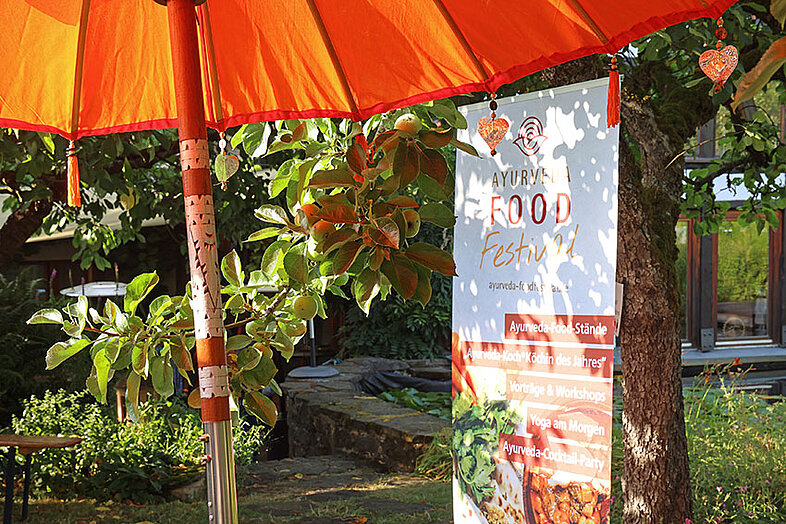 Stand mit ayurvedischen Speisen unter rotem Sonnenschirm beim Food Festival des Rosenberg Ayurveda Zentrums